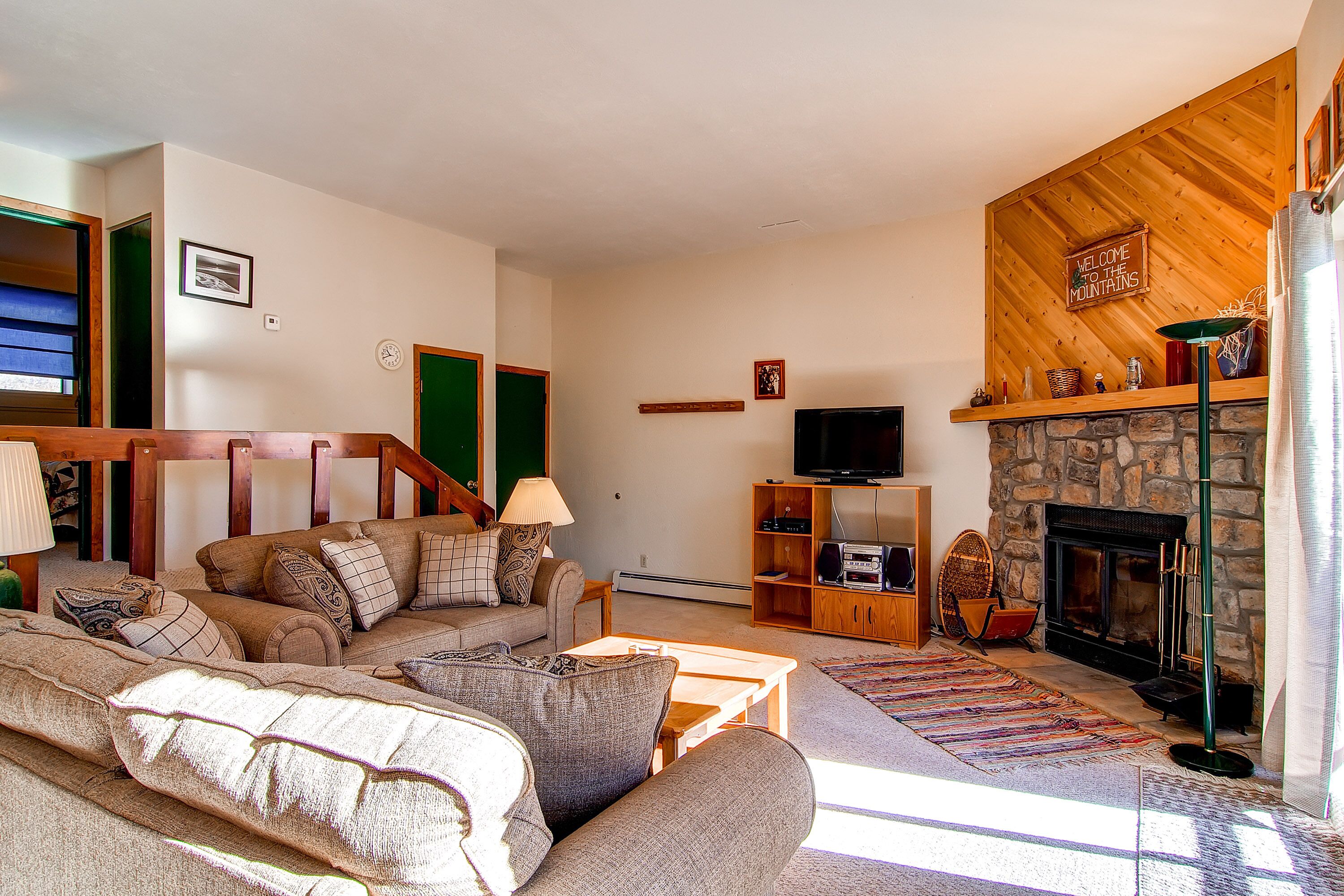 A cozy living room with a stone fireplace, a television, and a comfortable sofa.