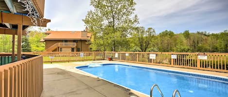 Une piscine avec une terrasse en bois, un drapeau et un bâtiment en arrière-plan.
