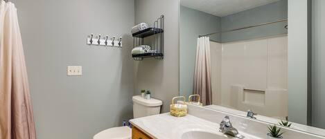A bathroom with a white sink, a mirror, a towel rack, a toilet, and a shower curtain.