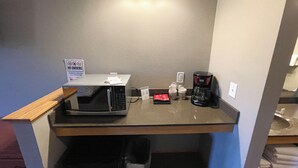 Une petite cuisine équipée d’un four à micro-ondes, d’une machine à café et d’un panneau indiquant qu’il est interdit de fumer.