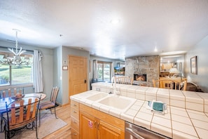 A spacious kitchen with a large island, a stone fireplace, and a dining area with a chandelier.