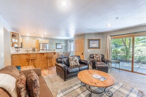A spacious living area with a kitchen, a dining table, and a large sliding glass door leading to an outdoor area.
