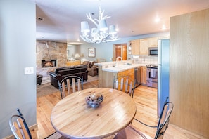 A modern kitchen with a central island, a stone fireplace, and a dining area with a round wooden table.