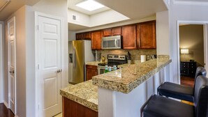 Una cocina con armarios de madera, electrodomésticos de acero inoxidable y encimera de granito.