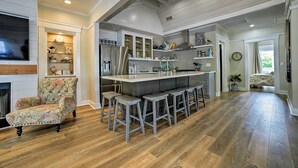 Une cuisine spacieuse dotée d’un îlot central, de tabourets de bar et d’une chaise décorative.