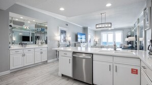 A modern kitchen with white cabinetry, a stainless steel dishwasher, and a large island with a sink. - Inn at Crystal Beach 408 * Gulf Front with Beach Chair Set. Onsite dining! (Destin)