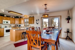 Une cuisine spacieuse dotée de meubles en bois, d’un îlot central et d’un coin repas avec une grande table et des chaises en bois.