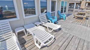 Terraza de madera con sillones de descanso y una mesita, con vista a la playa.