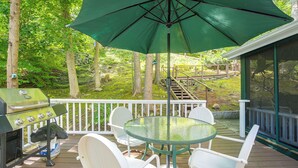 An outdoor deck with a grill, chairs, and a table under a green umbrella. - Dainty New Preston Cottage w/ Dock & Lake Views! (New Preston)
