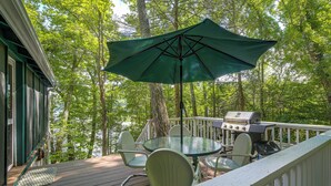 A deck with a table and chairs, a grill, and a green umbrella. - Dainty New Preston Cottage w/ Dock & Lake Views! (New Preston)