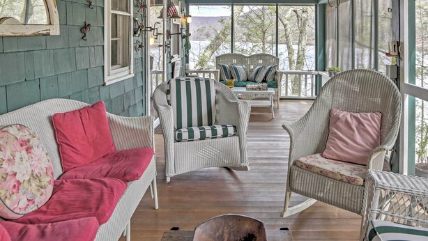 Eine überdachte Veranda mit Korbmöbeln, darunter eine Couch und Stühle, sowie ein Esstisch.