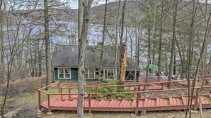 Eine Holzhütte mit einer Holzterrasse und einem grünen Sonnenschirm.