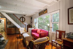 Ein Zimmer mit Treppe, einem roten Sofa, Korbmöbeln und einem Schild mit der Aufschrift 'Maple Danceland'.