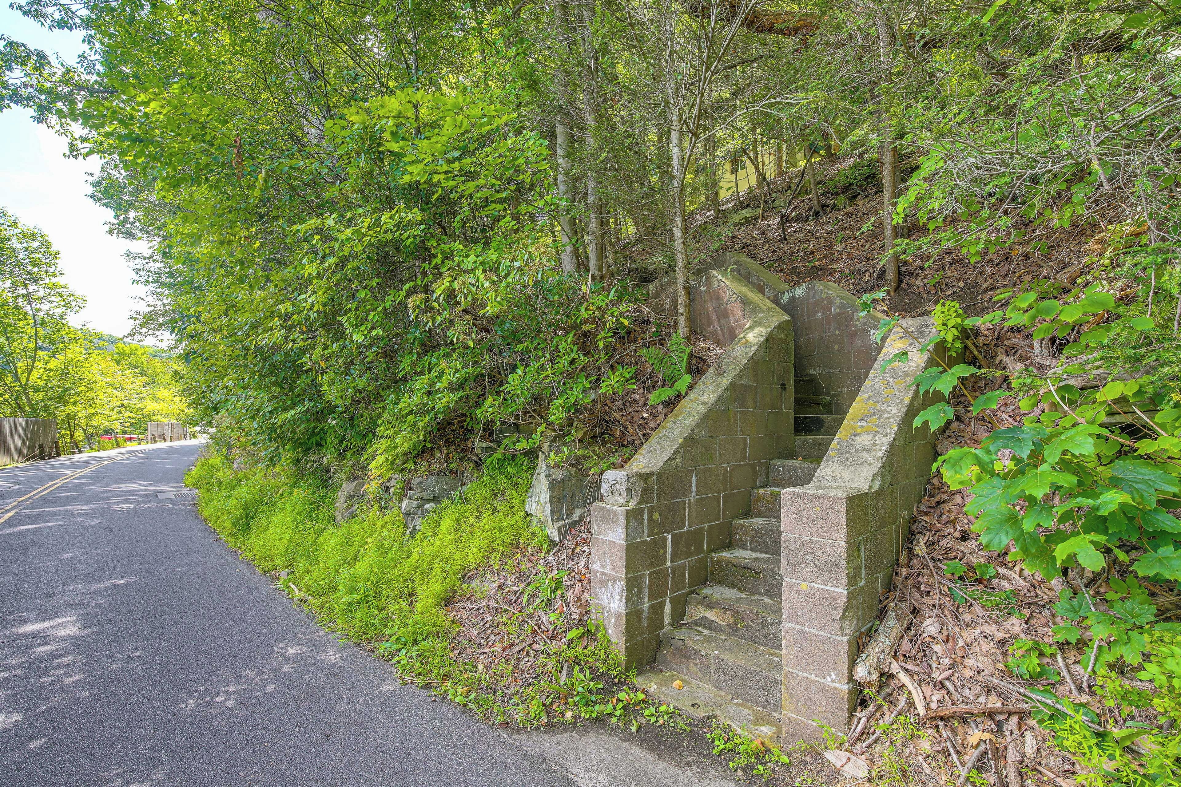 Une route étroite, bordée d’un escalier en pierre qui descend vers une zone boisée.