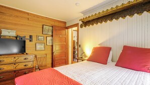 A bedroom with a wooden dresser, a television, a bed with a white quilt, and a red pillow. - Dainty New Preston Cottage w/ Dock & Lake Views! (New Preston)