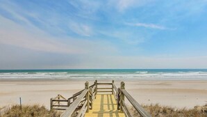 A wooden boardwalk leading to a beach with the ocean in the background.