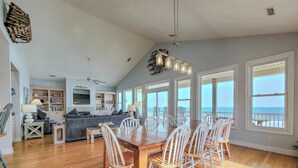 A spacious living area with a dining table, chairs, and a view of the ocean.