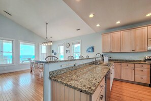A spacious kitchen with granite countertops, wooden cabinets, and a large island. - Lucky Enough – Pets Welcome, Ocean Views Included (Surf City)