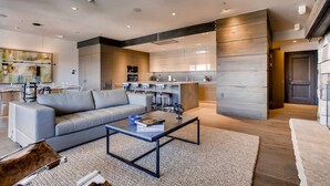 Een moderne woonkamer met een grijze bank, een salontafel en een vloerkleed.