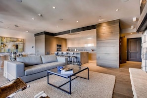 Un salon moderne avec un canapé gris, une table basse et un tapis.