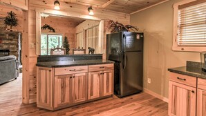 Een keuken in chaletstijl met houten kasten, een groot eiland en een zwarte koelkast.