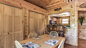 Een houten interieur met een eettafel, stoelen en een keukenhoek.