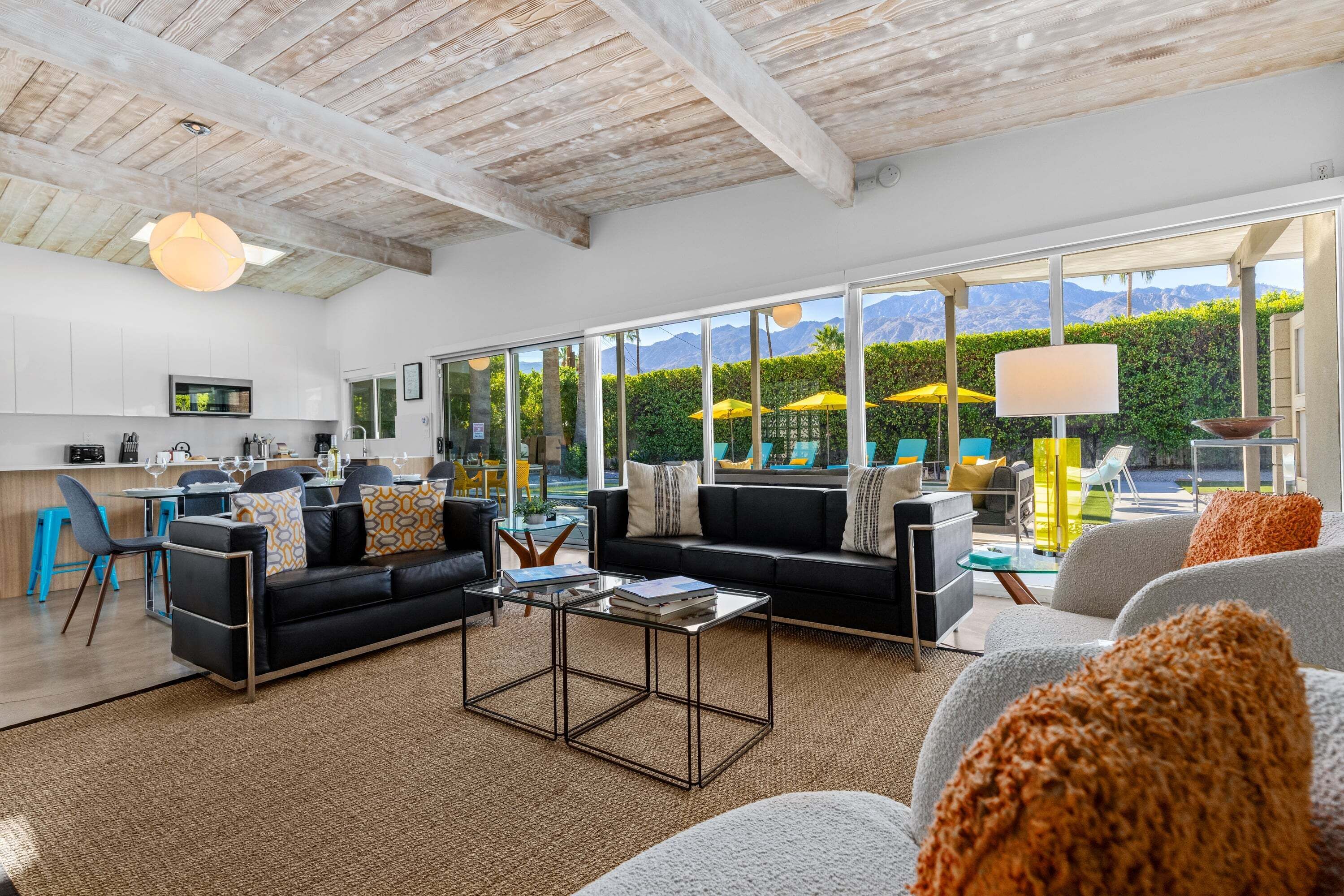 A spacious living area with a modern sofa, a coffee table, and a view of a mountain landscape through large windows.