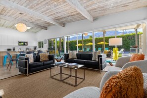 A spacious living area with a modern sofa, a coffee table, and a view of a mountain landscape through large windows.