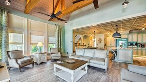 A spacious living room with a wooden ceiling, a white sofa, a coffee table, and a kitchen area with teal cabinets and a blue refrigerator. - Beautiful Luxury Southern Style Home located in Anna Maria - Walk easily to Beach, Sleeps 6! (Anna Maria)