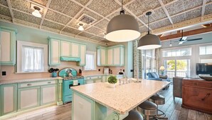 A spacious kitchen with teal cabinetry, a large island with bar stools, and a decorative ceiling. - Beautiful Luxury Southern Style Home located in Anna Maria - Walk easily to Beach, Sleeps 6! (Anna Maria)