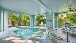 A covered swimming pool with a tiled deck, lounge chairs, and a barbecue grill. - Beautiful Luxury Southern Style Home located in Anna Maria - Walk easily to Beach, Sleeps 6! (Anna Maria)