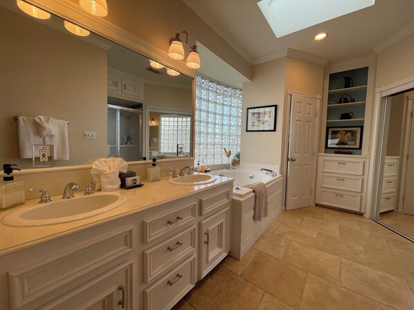 A spacious bathroom with two sinks, a large mirror, and a walk-in shower.