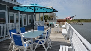 A wooden deck with a table and chairs, an umbrella, and a view of the water. - 
Fabulous Waterfront Fishing and Sunsets!   Free Night with Weekly rental. (Galveston)