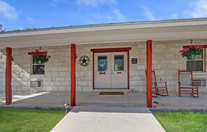 Um edifício com fachada de pedra, uma porta branca com emblema de estrela e colunas emolduradas por vermelho.