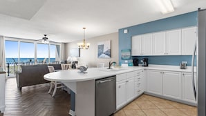 A modern kitchen with a large island, white cabinets, and a view of the ocean. - IP 213: Starlight Retreat - Kick back, relax, and enjoy Gulf-Front Living! (Fort Walton Beach)