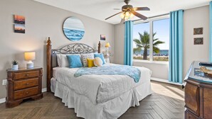 A bedroom with a bed, a nightstand, a ceiling fan, a window with curtains, and artwork on the walls. - IP 213: Starlight Retreat - Kick back, relax, and enjoy Gulf-Front Living! (Fort Walton Beach)