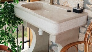 A bathroom with a stone wall, a sink, a green watering can, and a wicker chair with a red cushion. - Vacation house with PRIVATE garden, pool, table tennis and soccer. Max 4 persons (Svetvincenat)