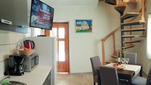 A modern kitchen with a flat-screen TV, a coffee maker, and a microwave. There is a dining area with a table and chairs, and a staircase leading to another level. - Vacation house with PRIVATE garden, pool, table tennis and soccer. Max 4 persons (Svetvincenat)