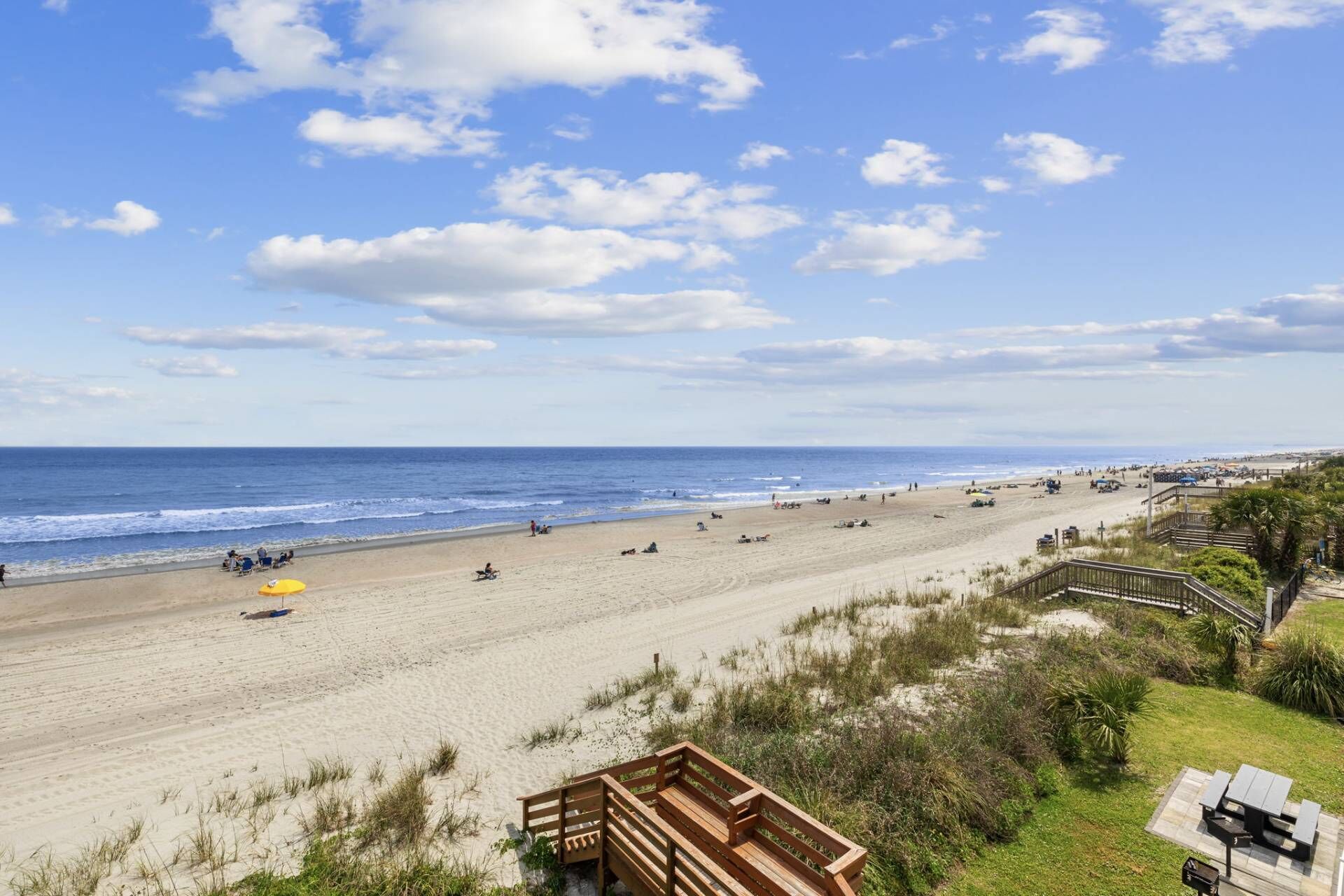 Une plage avec une terrasse en bois et des tables de pique-nique donnant sur l’océan.