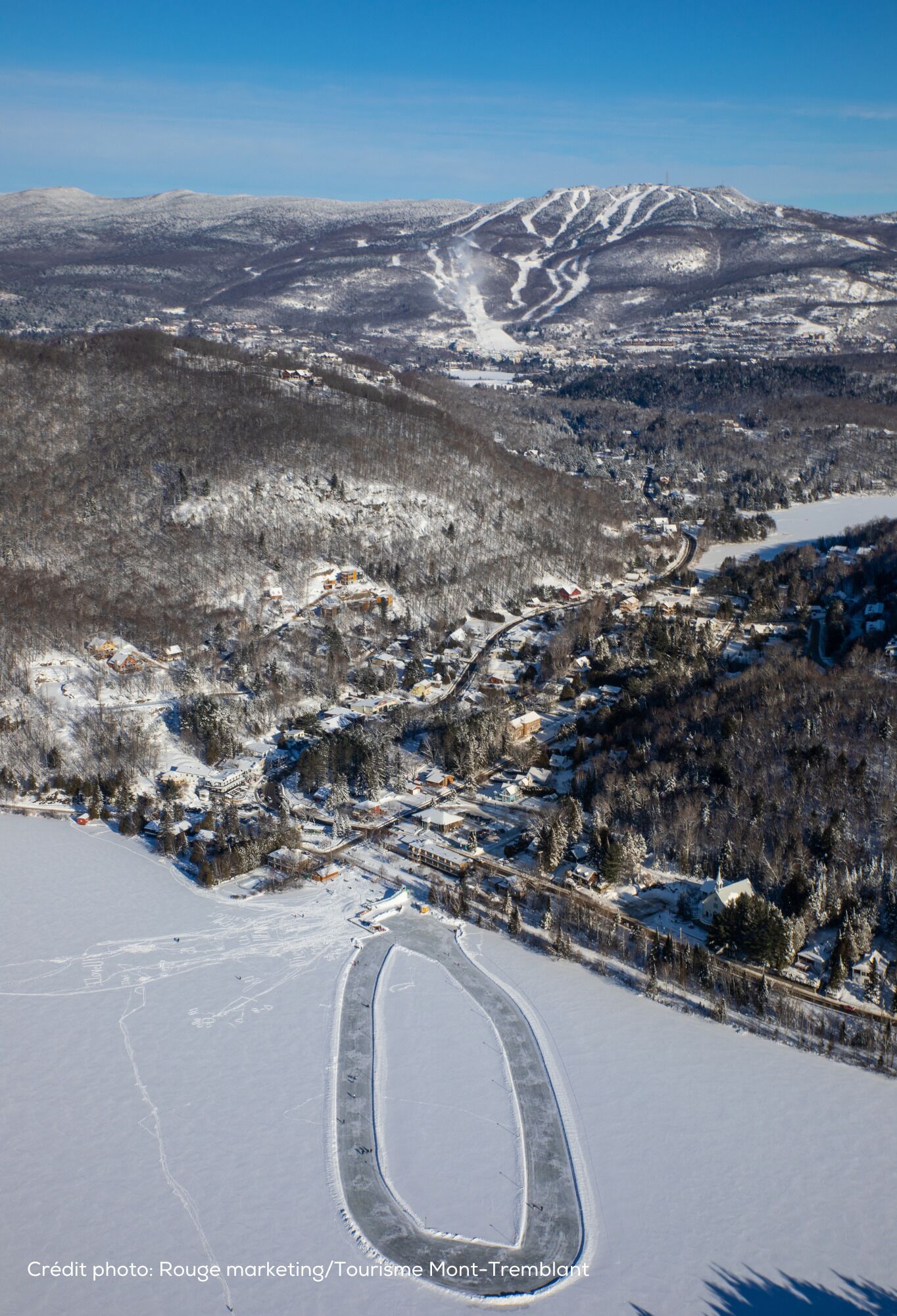 A snow-covered landscape with a ski resort, including ski trails and a mountain in the background.