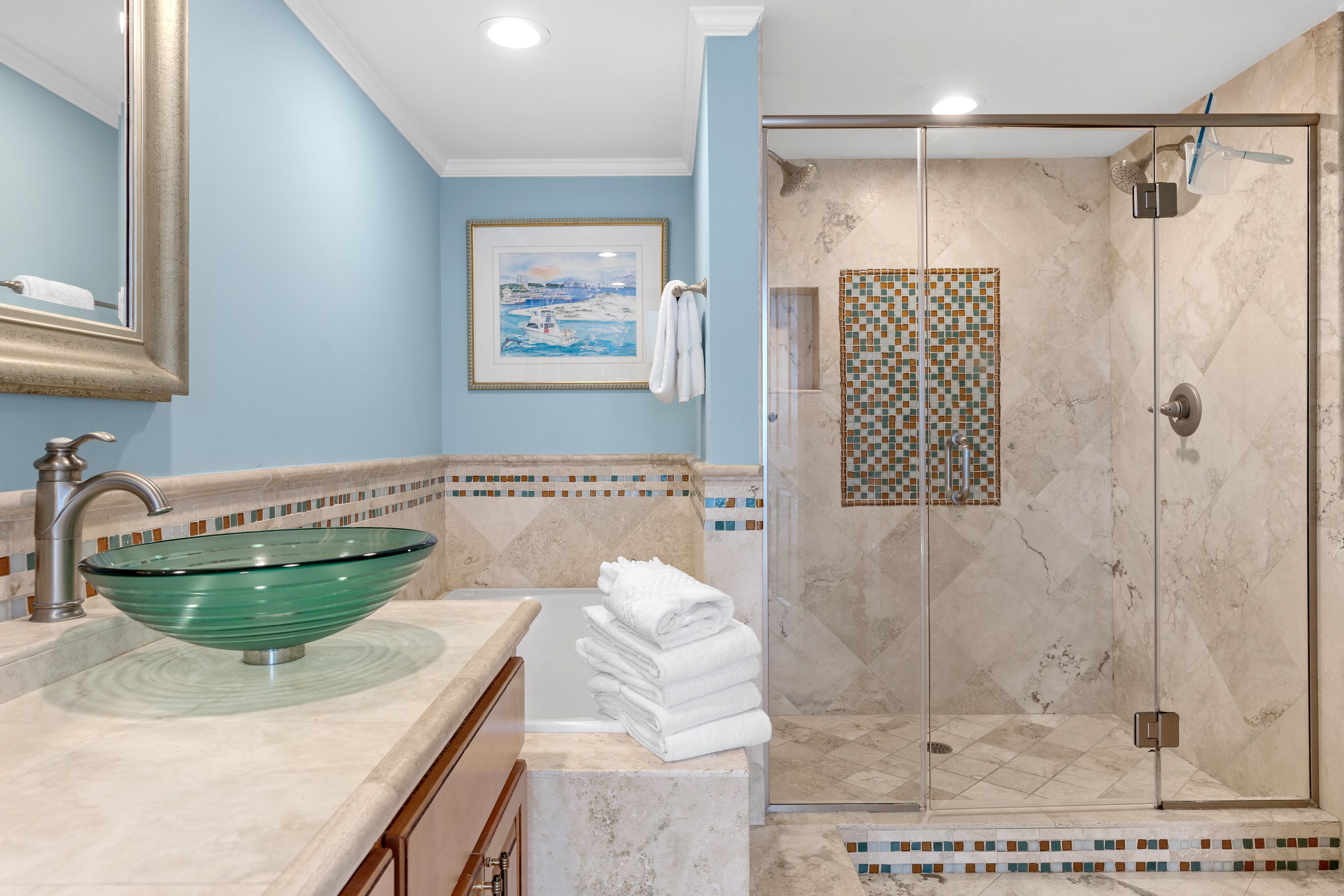 A bathroom with a glass bowl sink, a shower with a glass door, and a tiled shower floor.