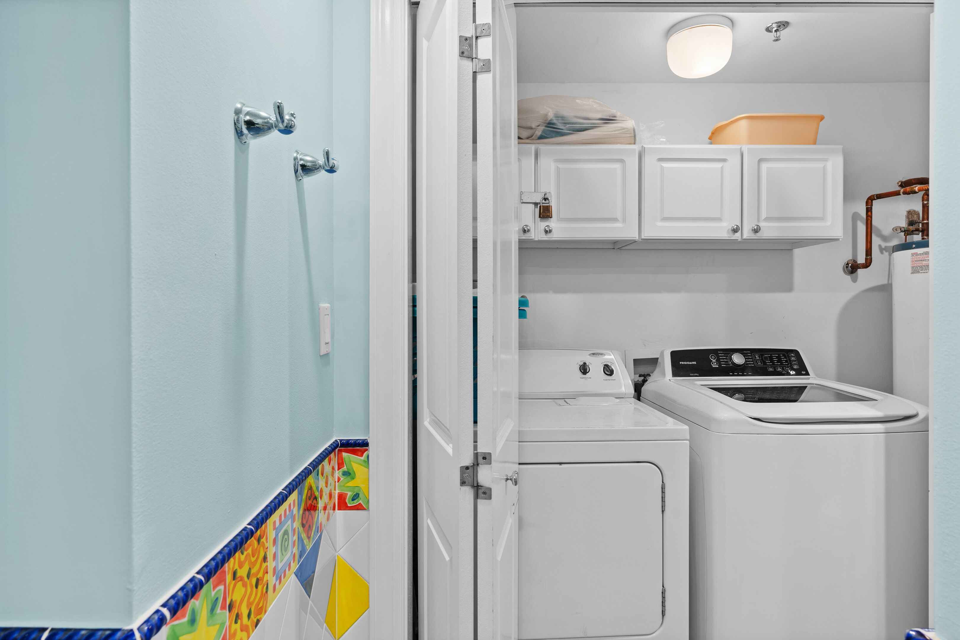 Une petite buanderie comprenant un lave-linge, un sèche-linge et un petit placard placé au-dessus du sèche-linge.