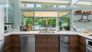 Eine moderne Küche mit einem großen Fenster, Edelstahlgeräten und Holzschränken.
