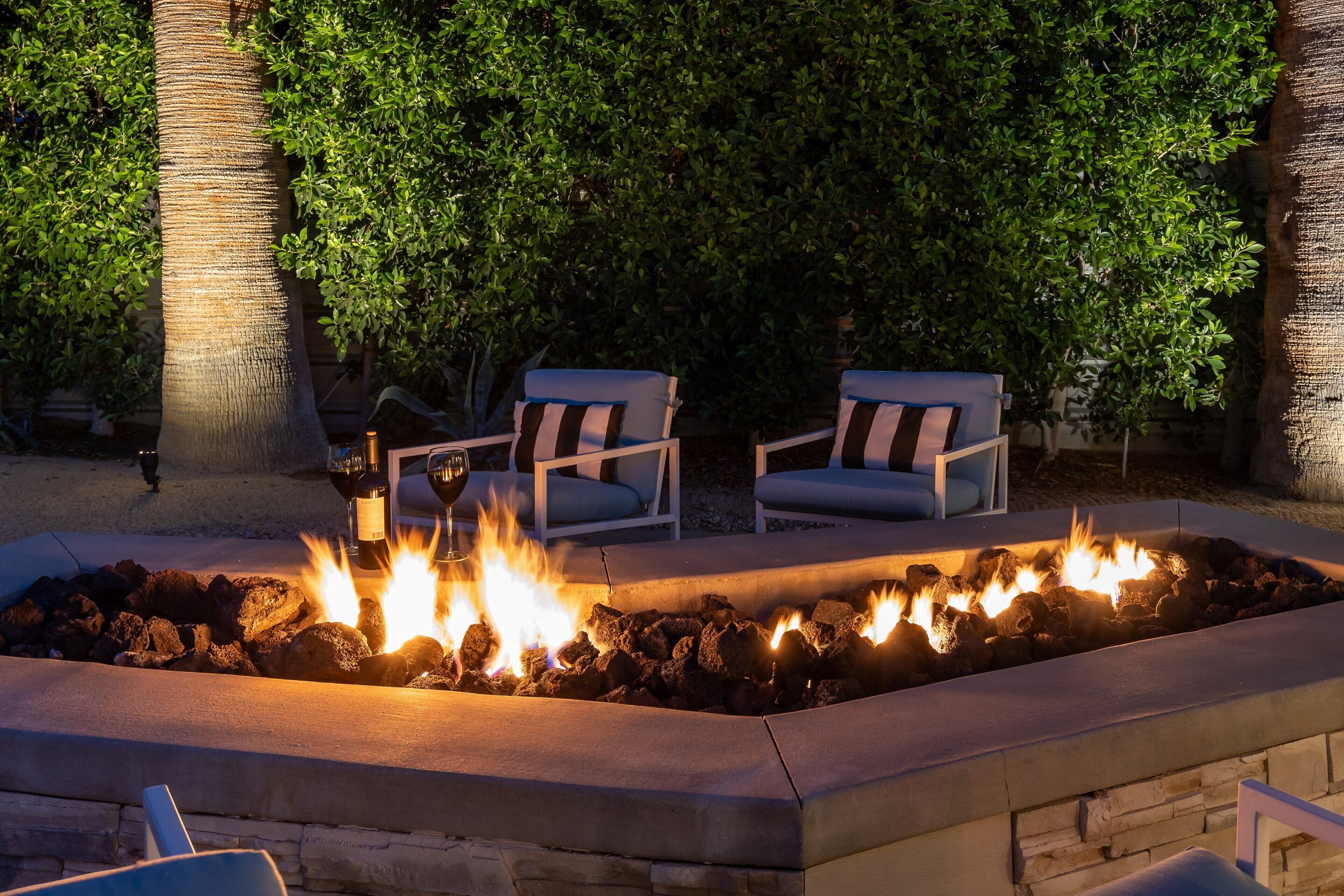 A fire pit area with seating, surrounded by greenery.