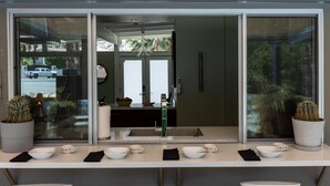 Ein modernes Badezimmer mit einem großen Spiegel, weißen Waschbecken und Topfpflanzen.