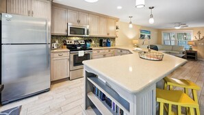 Una cucina moderna con elettrodomestici in acciaio inossidabile, un'isola centrale e un'area pranzo con sedie gialle.