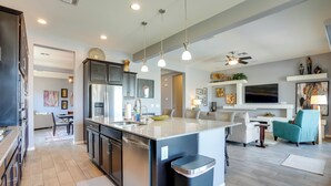 A modern kitchen with a central island, built-in appliances, and pendant lighting.