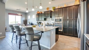A modern kitchen with a central island, stainless steel appliances, and pendant lighting.