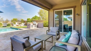 A covered patio with a pool, outdoor furniture, and a sliding glass door leading to a backyard.