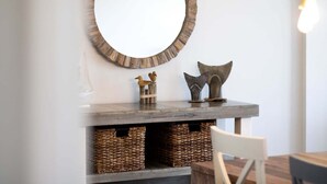 A wooden console table with wicker baskets, a round mirror, and decorative fish sculptures. - Beachfront Walkout – Ground-Floor Oceanfront Retreat w/ Private Sand Access & Heated Pool (Cape Canaveral)